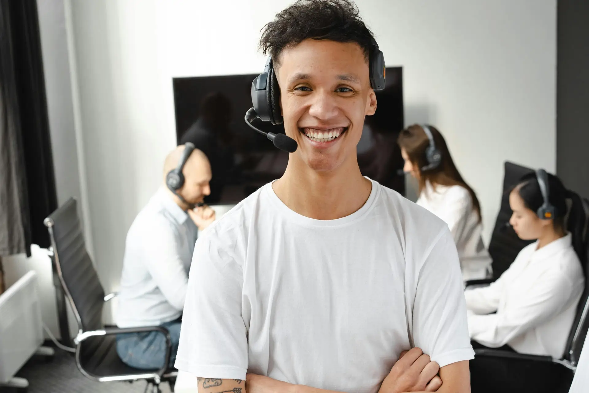 Lachende helpdeskmedewerker met headset in een IT-supportteamomgeving